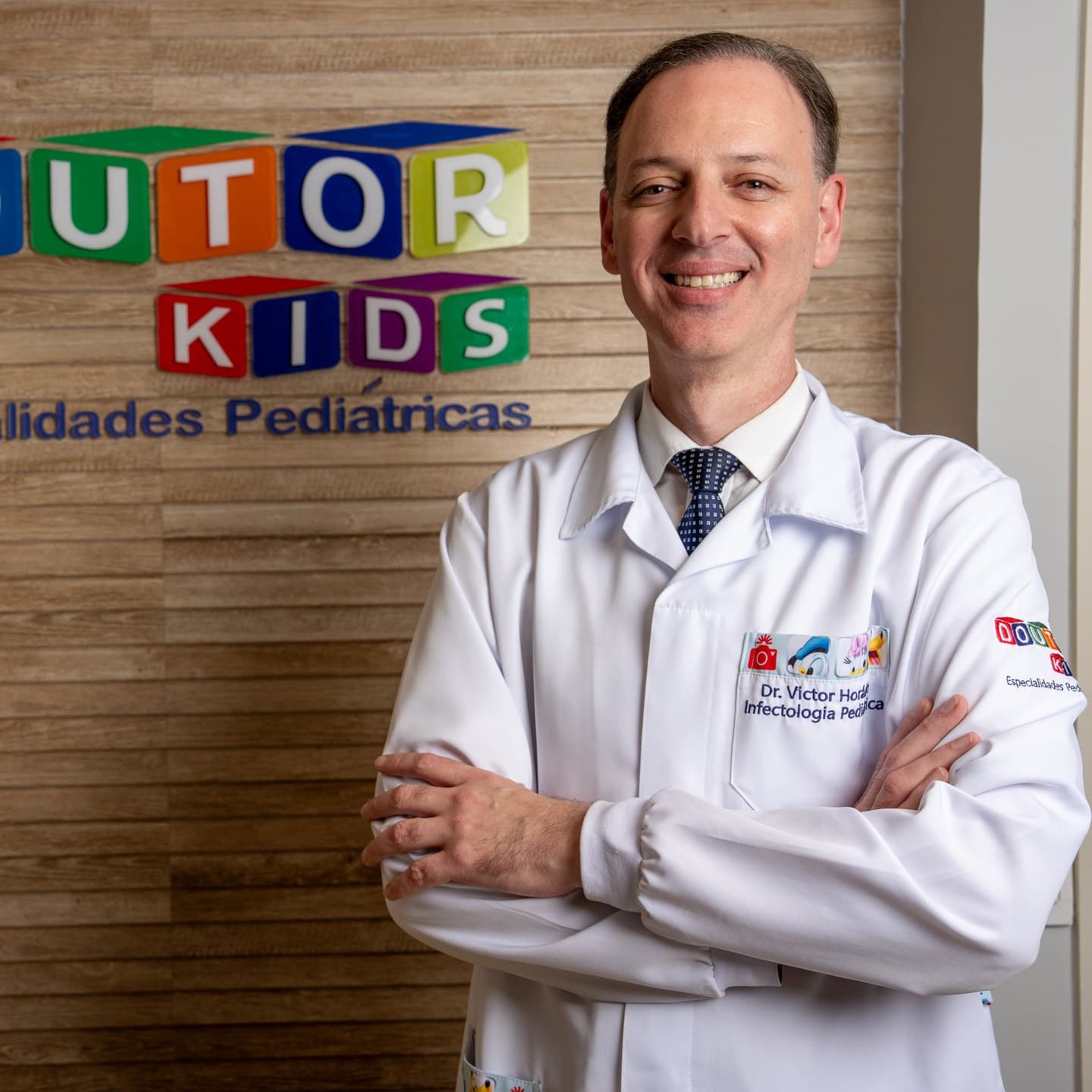 Dr. Victor Horácio de jaleco branco, de braços cruzados no consultório